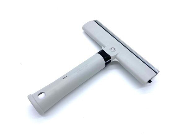 A white squeegee with black handle on top of a table.