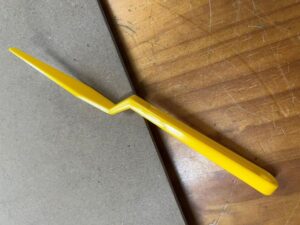A yellow pencil is on the floor next to some paper.