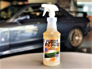 A bottle of orange adhesive remover sitting on top of a table.