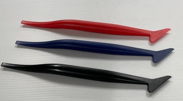 Three different colored pens are sitting on a table.
