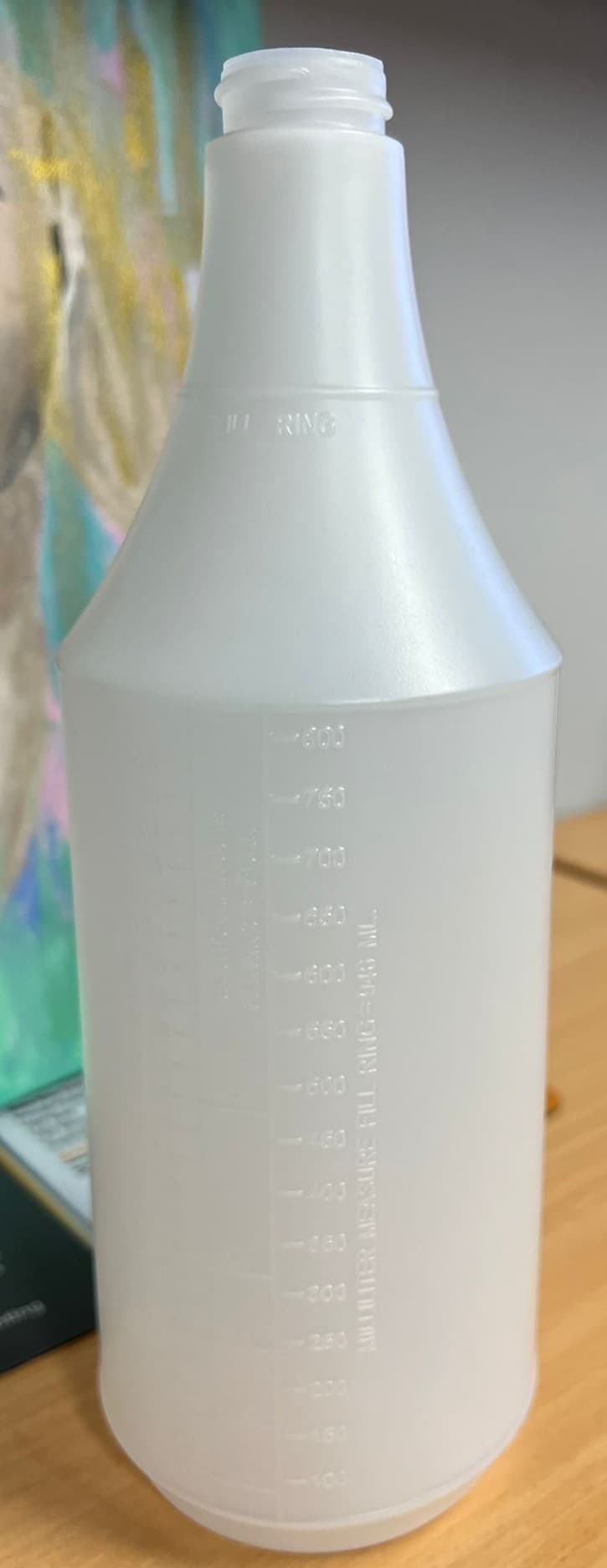 A bottle of liquid with a measuring cup on top.